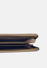 Bruine portemonnee met meerdere vakken, gouden rits en een gestructureerd oppervlak. Bevat een extra ritsvak en leren accenten.