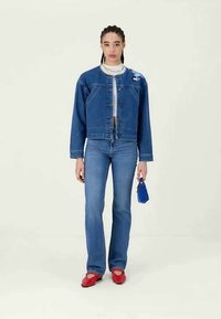 Jeansjacka med broderade detaljer, blå jeans, röda ballerina skor och en liten blå väska. Avslappnad passform, klassisk design och standarddetaljer.