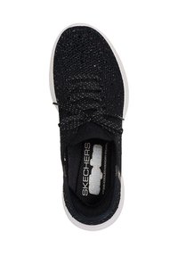 Zapatilla negra tipo slip-on de Skechers con parte superior de punto, cordones negros, adornos plateados y suela blanca, vista desde arriba.