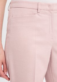 Lichtroze op maat gemaakte broek met een gestructureerde stof, subtiel diamantpatroon en een platte voorkant met een zijzak.