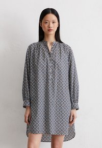 Langärmliges Tunika-Kleid in navy, weiß und gelb mit geometrischem Muster; verfügt über einen Stehkragen und leichte Raffung an den Schultern.