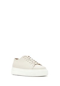 Beige lage leren sneaker met dikke witte plateauzool en bijpassende beige veters, schuin weergegeven om de buitenkant en voorkant te tonen.