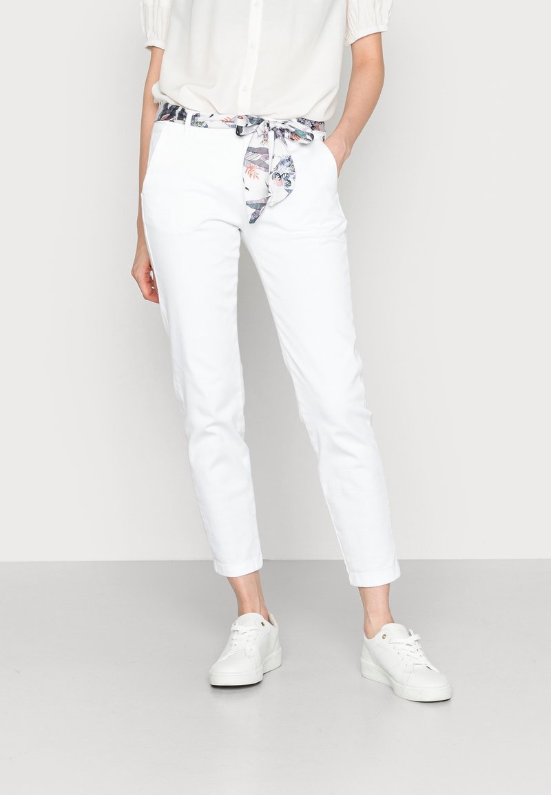 White cotton pants with a floral-patterned belt, featuring a tailored fit and cuffed ankles, paired with white sneakers.