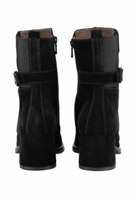 Stivali alla caviglia in suede nero con tacco quadrato, pannelli laterali elastici, cintura decorativa e chiusura con zip sul lato esterno.
