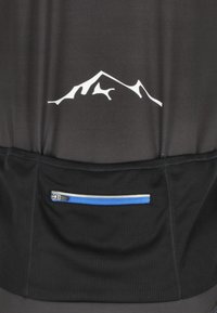 Μαύρο ποδηλατικό jersey στην πλάτη με λευκό στυλιζαρισμένο λογότυπο βουνού πάνω από μια μαύρη υφασμάτινη τσέπη με οριζόντια μπλε φερμουάρ.