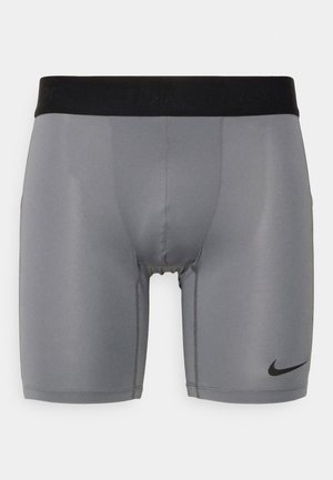Grå idrettsshorts med svart elastisk midjebånd, med en svart Nike-logo på nedre venstre side, laget av glatt, stretchy stoff.