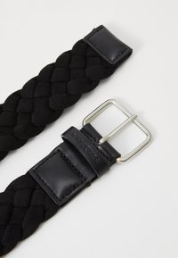 Black braided belt made of textured material with a silver metal buckle and a black leather strap. Features embossed brand logo on leather.