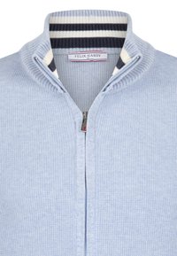 Hellblaues, gestricktes Zip-Up-Pullover mit einem gerippten Kragen in Marineblau und Weiß sowie einem silbernen Reißverschluss mit rotem Akzent.