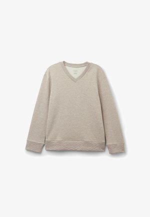 Ljust beige långärmad tröja med V-hals, texturerade ärmslut och en vågig mönstrad nederkant. Tillverkad av mjukt tyg, har en avslappnad passform.
