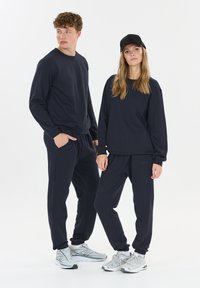 Donkerblauwe, lange mouwen sweatshirt met bijpassende joggers, gemaakt van zacht materiaal. Kenmerkt een relaxte pasvorm, geribde manchetten en een elastische tailleband.