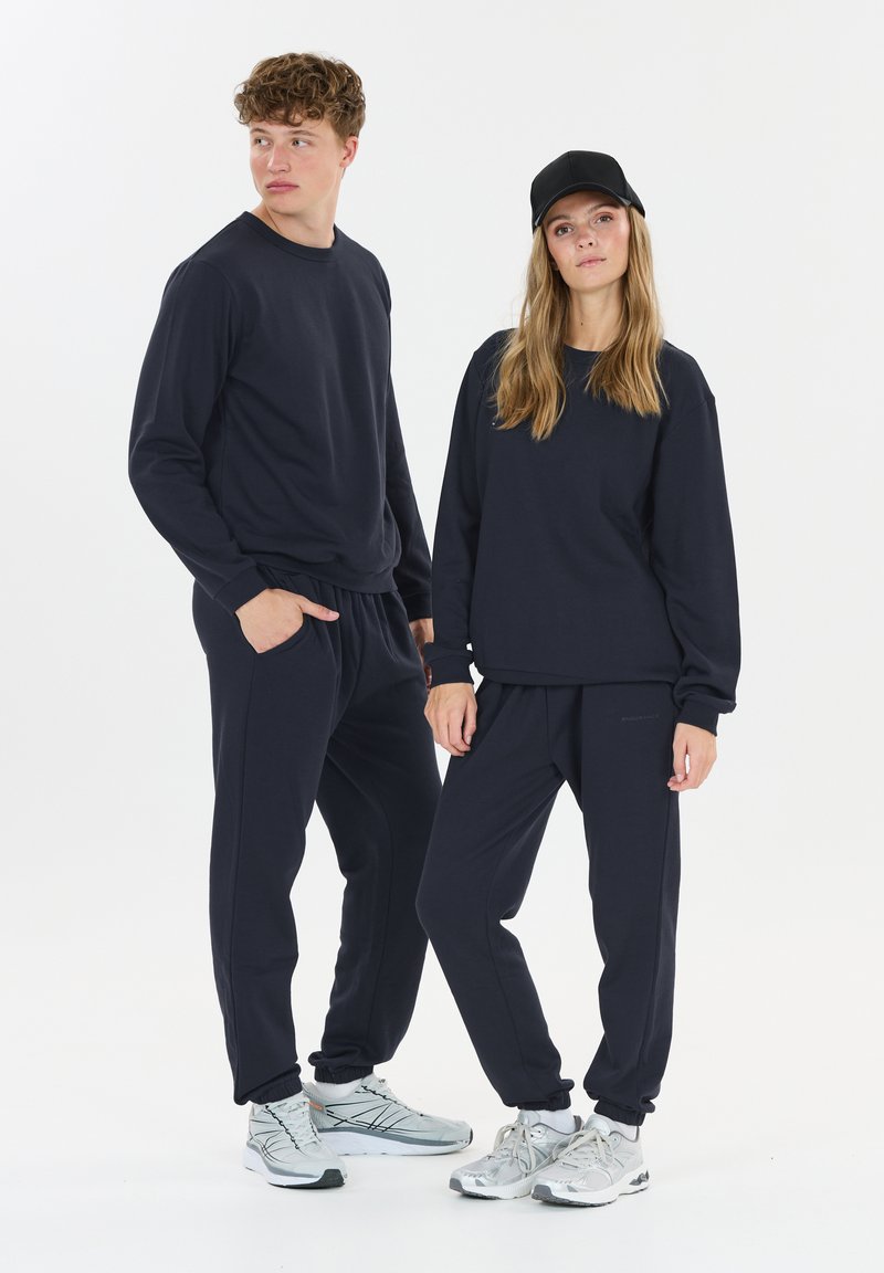 Donkerblauwe, lange mouwen sweatshirt met bijpassende joggers, gemaakt van zacht materiaal. Kenmerkt een relaxte pasvorm, geribde manchetten en een elastische tailleband.