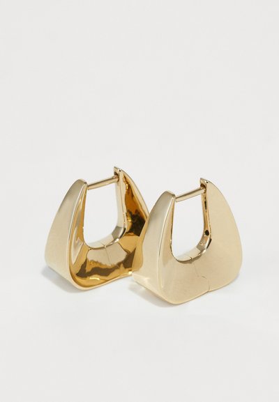Guldmetal hoops øreringe med et skulpturelt, vinklet design. Glat overflade med blank finish, der har en lille stanglås.
