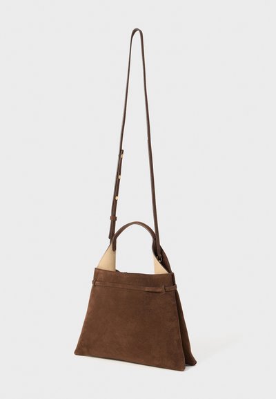 Sac à main en daim marron avec un design structuré, doté d'une poignée courte et d'une longue sangle réglable. Texture lisse, style minimaliste.