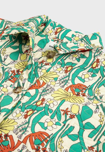 Col col matelassé boutonné avec un motif floral et de feuilles coloré en tons verts, jaunes, orange et blancs.