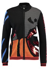 Svart zip-up-tröja med abstrakt popkonstansikte, röda paljetter på läpparna, blå och röda ärmsträck och mönstrade detaljer i orange och grått.