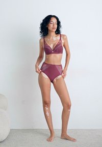 Burgundy lingerie set featuring a bra with mesh overlays and a high-waisted bottom, smooth texture, and adjustable straps.