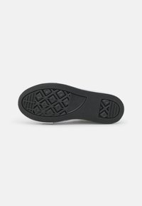 Suela de zapato de goma negra con un patrón texturizado que presenta formas geométricas para tracción y estabilidad. Los bordes son suaves y redondeados.