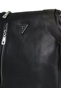 Borsa a spalla in pelle nera con zip argento e logo triangolare in argento. Include una tracolla texture per il trasporto.