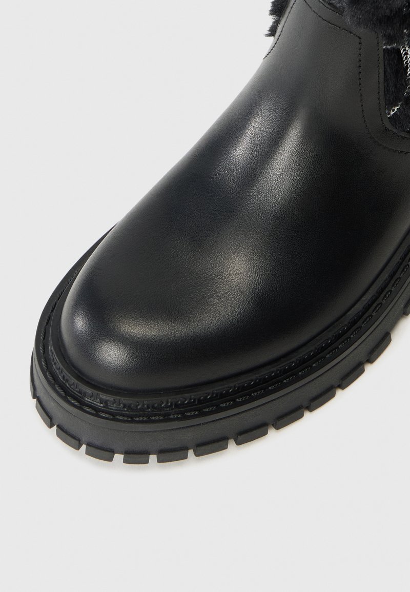 Schwarze Leder-Ankle-Boots mit runder Zehenform, strukturiertem schwarzen Gummisohle, Steppdetail und weichem Fellfutter im oberen Bereich.