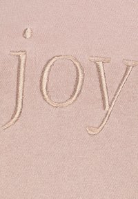 Roze stof met het woord "joy" in lichtbeige borduursel. Glad oppervlak met een zachte, subtiele glans en geen extra patronen.