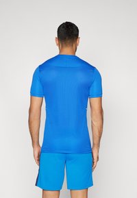 Blå atletisk skjorte og shorts; korte ermer, rund hals, teksturert stoff, tettsittende design med hvite detaljer på sidene.