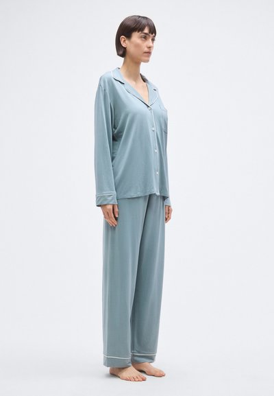 Világoskék pizsama szett puha anyagból; hosszú ujjú felső zsebbel és gombos záródással, széles szárú nadrággal, melyen mandzsetták találhatók.