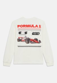 Λευκό T-shirt με μακριά μανίκια που φέρει εκτύπωση με γραφικό μιας φόρμουλας 1, κόκκινο κείμενο, βελάκια κατεύθυνσης και μαύρο καρό μοτίβο.