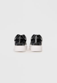Black sneakers with patent leather finish, featuring a textured pattern and white rubber sole. Logo printed on the back.