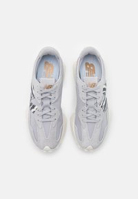 Zapatillas deportivas grises con una mezcla de suave gamuza y materiales de malla, con un acento de estampado de cebra, punta redondeada y cordones texturizados.