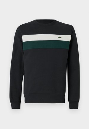 Mørk sweatshirt med svart bunn, prydet med grønne og hvite horisontale striper over brystet og en liten brodert logo til venstre.