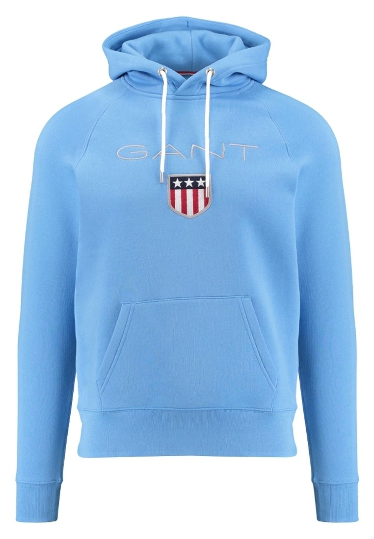 Jasnoniebieska bluza z kapturem wykonana z miękkiego materiału, z kieszenią kangurką, kapturem ze sznurkiem oraz haftowanym logo GANT z czerwono-białym wzorem tarczy.
