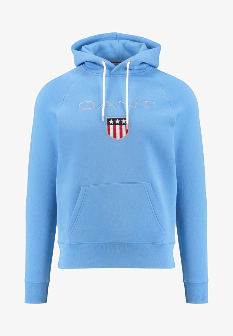Jasnoniebieska bluza z kapturem wykonana z miękkiego materiału, z kieszenią kangurką, kapturem ze sznurkiem oraz haftowanym logo GANT z czerwono-białym wzorem tarczy.