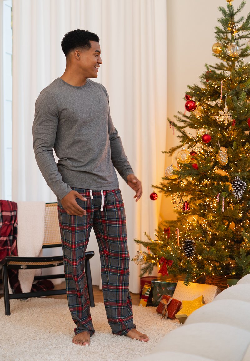 Gray long-sleeve shirt paired with plaid pajama pants in gray, red, and green, featuring an elastic waistband and drawstring.