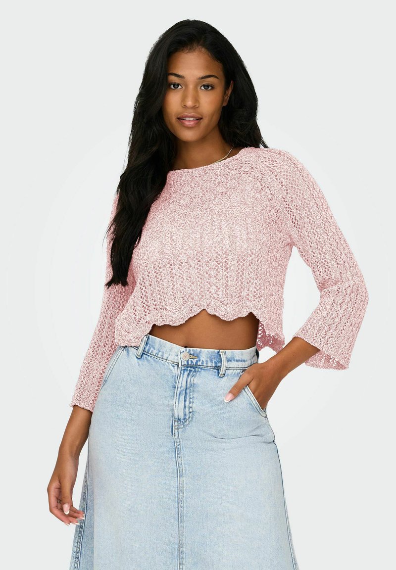 Top court en tricot rose avec un ourlet festonné et des manches trois-quarts, associé à une jupe en denim taille haute. Design en tissage ouvert texturé.