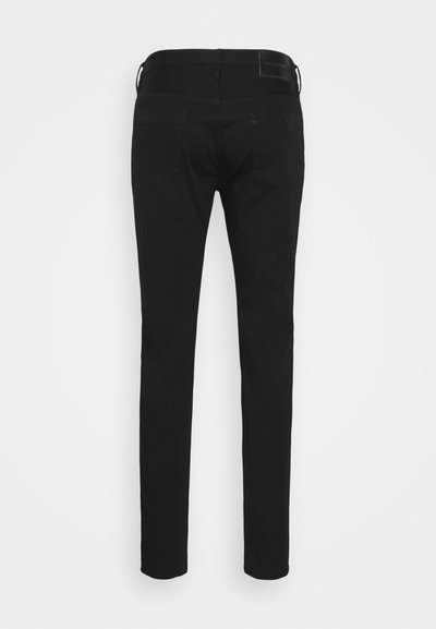 Jeans noirs avec une coupe slim, présentant un design simple à l'arrière, deux poches arrière et une texture lisse. La ceinture comprend une étiquette avec le logo.