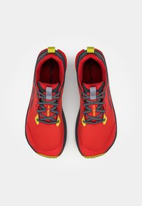Chaussures de sport rouges avec une tige en maille, semelle noire, lacets gris et accents jaunes. Comprend un col rembourré et une surface texturée.