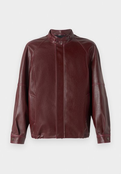 Burgundy leather jacket with a high collar, zip closure, raglan sleeves, side pockets, and a smooth texture. Features snap buttons on cuffs.