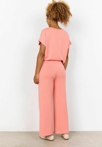 Roze loungewear set met een losse top met korte mouwen en wijde broek. Zacht materiaal met een elastische tailleband en een relaxte pasvorm.
