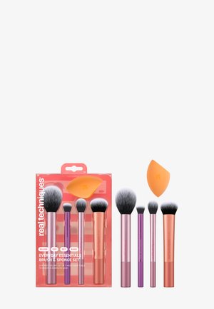 Set of five makeup brushes in pink and purple handles with white and black bristles, plus an orange makeup sponge.