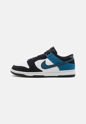 Baskets basses Nike avec panneaux noirs, blancs et bleu sarcelle, lacets noirs et semelle blanche avec semelle extérieure noire, vues de côté.