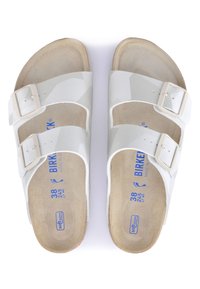 White Birkenstock sandals with two adjustable buckles, smooth upper material, and soft, beige suede footbed. Size markings visible on insole.