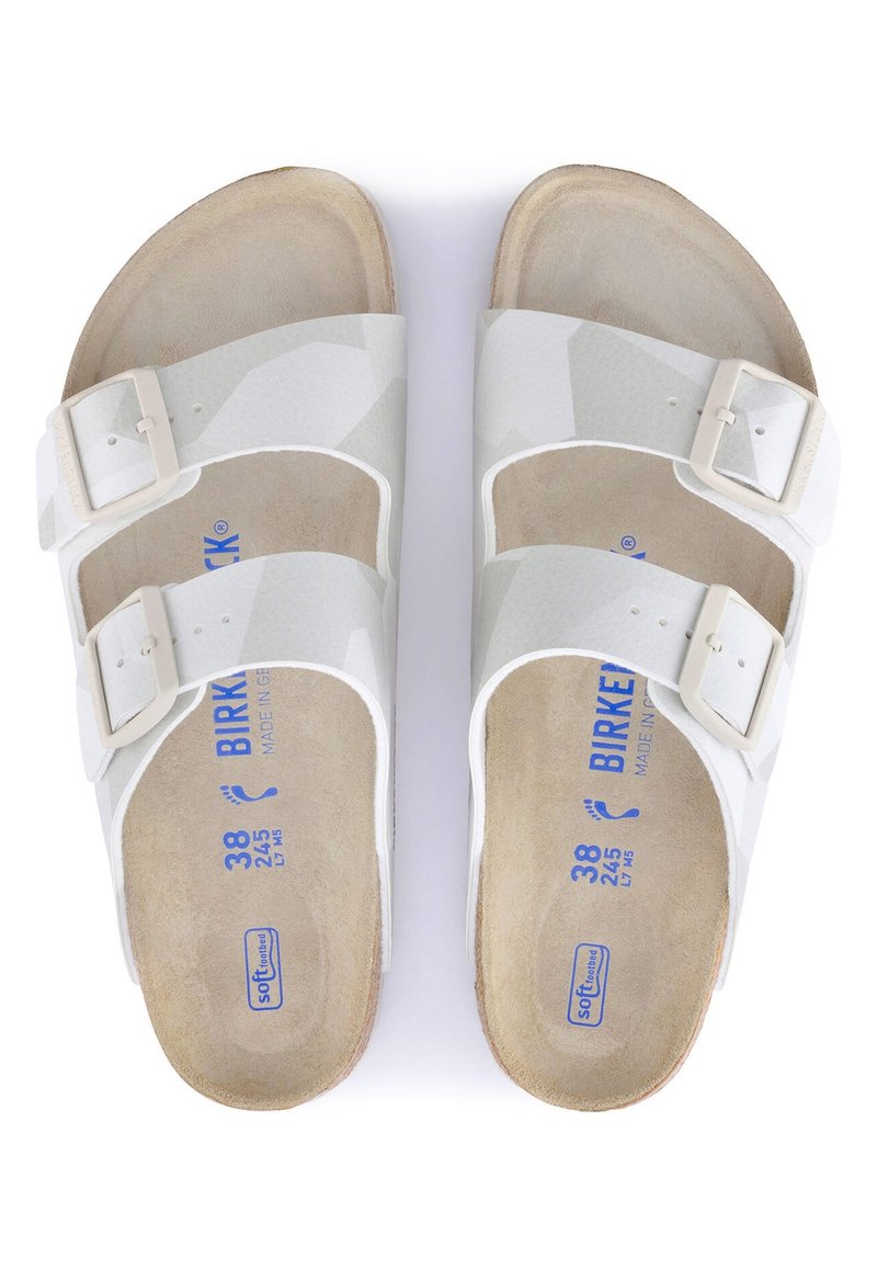 Vita Birkenstock sandaler med två justerbara spännen, slätt ovansidans material och mjukt, beige mockasinsula. Storleksmarkeringar synliga på innersulan.