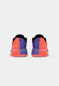 Sporta apavi ar melnu, oranžu un purpura dizainu. Tekstūrēta augšdaļa apvieno sietu un sintētiskos materiālus. Izteikta papēža dizains.