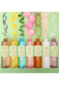 Syv transparente flasker med toner i forskjellige farger: brun, gul, blå, rosa, oransje, hvit og lilla, stilt opp på en grønn bakgrunn med botaniske elementer.