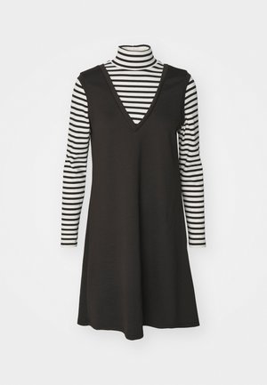 Vestido preto sem mangas com decote em V, sobreposto a uma blusa de manga longa listrada em preto e branco. Tecido em algodão, corte solto, listras verticais.