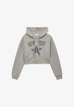 Haut en hoodie gris, coupé, avec une fermeture éclair à l'avant, une grande capuche et le motif "NEW YORK" avec un graphique d'étoile sur la poitrine. Fabriqué en tissu doux.