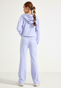 Lys lilla hættetrøje med snøre og bukser med baglomme i matchende farve, med blød tekstur og afslappet pasform.