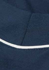 Mörk marinblått tyg med texturerad yta; har en vit accentrand. Innehåller distinkta sektioner med olika stickningsmönster.