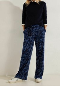 Marina vida byxor med ett blått lövmönster, med en elastisk midja med dragsko och sidofickor, kombinerat med en svart topp.