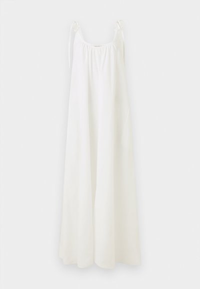 Λευκό μάξι φόρεμα χωρίς μανίκια με δέσιμο στους ιμάντες των ώμων και σούρα στη λαιμόκοψη, κρεμασμένο σε απλό φόντο.